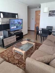 a living room with a couch and a tv at Agradable Dpto Calama Centro in Calama
