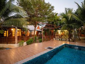 a house with a swimming pool in front of a house at บ้านกูรูรีสอร์ท in Ban Thung Satong