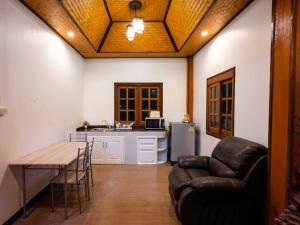 a living room with a couch and a table and a kitchen at บ้านกูรูรีสอร์ท in Ban Thung Satong