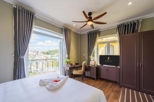a bedroom with a bed with a ceiling fan and a balcony at Mallorie Hotel Dalat in Xuan An