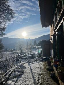 ein schneebedeckter Hof mit der Sonne im Hintergrund in der Unterkunft DADU'S Cafe in Sainj