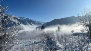 Ein schneebedecktes Feld mit Bergen im Hintergrund in der Unterkunft DADU'S Cafe in Sainj
