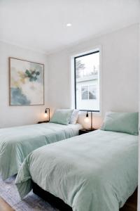 a white bedroom with two beds and two windows at Sixty - House 1 in Currie