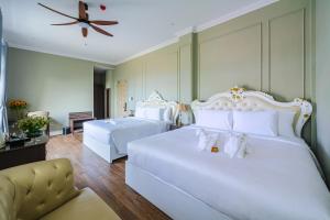 a bedroom with two white beds and a ceiling fan at Mallorie Hotel Dalat in Xuan An +54 photos