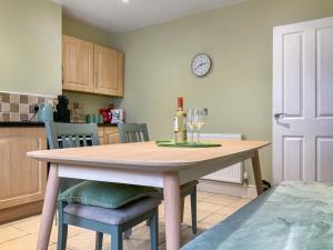 a kitchen with a table and a clock on the wall at Paddy's Cottage in Flookburgh