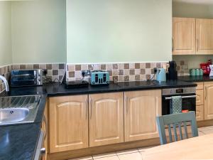 a kitchen with wooden cabinets and black counter tops at Paddy's Cottage in Flookburgh