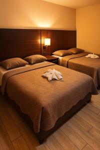 two beds in a hotel room with towels on them at Hotel Boutique 4 Estancias in San Ramón