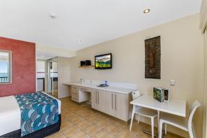 a hotel room with a bed and a desk at Aquarius On The Beach in Townsville