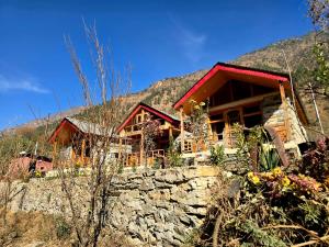 a log cabin in the mountains with a stone wall at River View Sunrise Cottages Tirthan Valley in Kulu