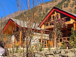 a log cabin with a mountain in the background at River View Sunrise Cottages Tirthan Valley in Kulu +26 photos