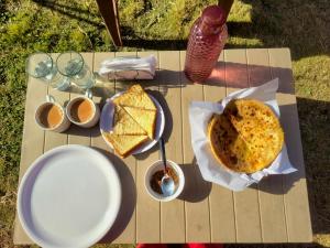 a picnic table with a sandwich and cups of coffee at River View Sunrise Cottages Tirthan Valley in Kulu