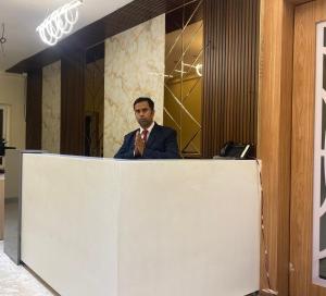a man in a suit and tie standing behind a counter at Hotel safal exotica in Puri