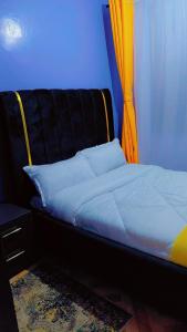 a bed in a room with a black and orange curtain at LJ Homes in Kisii