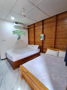 two beds in a room with wooden walls at Beach cabin uppuveli in Trincomalee
