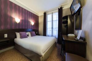 a bedroom with a bed and a desk and a television at Hotel Victor Massé in Paris