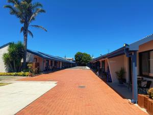 a red brick road between buildings with a palm tree at Lakeside Motel Waterfront in Lakes Entrance