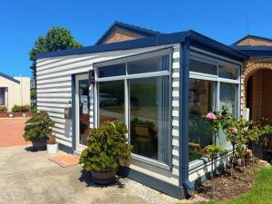 a tiny house with large windows in a yard at Lakeside Motel Waterfront in Lakes Entrance