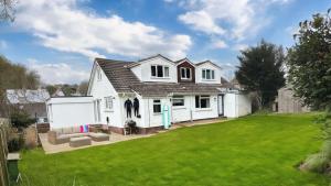 a white house with a green lawn at Croyde Broadlands 5 Bedrooms in Croyde
