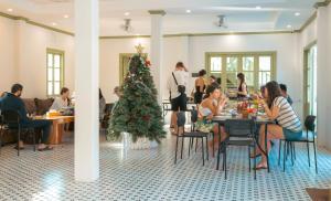 a group of people sitting at tables with a christmas tree at White Elephant Hostel in Luang Prabang