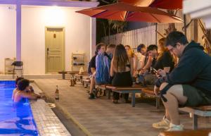 a group of people sitting on benches next to a swimming pool at White Elephant Hostel in Luang Prabang +46 photos