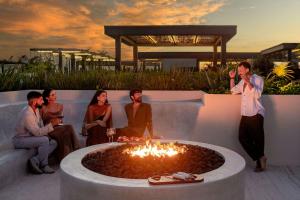 a group of people sitting around a fire pit at Bloom Tulum, Apartments by Marriott Bonvoy in Tulum +110 photos