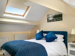 a bedroom with a blue bed with blue pillows at Paddy's Cottage in Flookburgh