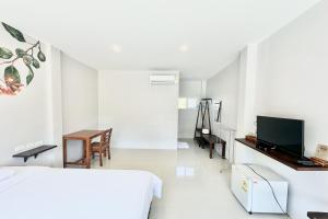 a bedroom with a bed and a desk and a television at Be Leaf Resort SHA in Thalang