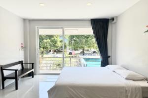 a bedroom with a bed and a large window at Be Leaf Resort SHA in Thalang