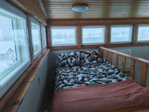 a bed in the corner of a room with windows at Lumikko Aurora Loft in Enontekiö +6 photos