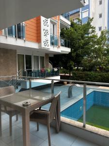 a balcony with a table and chairs next to a swimming pool at Alfa Apart Hotel in Antalya