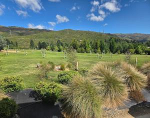 a field of grass with trees and mountains in the background at Barn Apartment in Earnscleugh