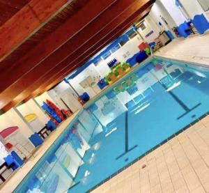 a large swimming pool with blue tables and chairs at Mason's Morecambe Memories in Heysham