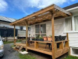 a wooden pergola on a deck in front of a house at Rest & Relax Holiday Home in Whangarei