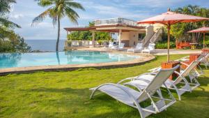 a group of chairs and umbrellas next to a swimming pool at El Mar Resort in Sampong