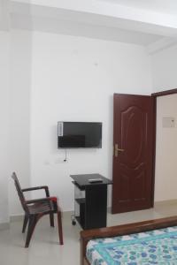 a bedroom with a bed and a desk and a tv at Anand Lodge in Thiruchendur