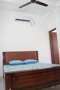 a bed with blue pillows and a ceiling fan at Anand Lodge in Thiruchendur