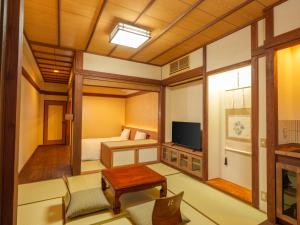 a room with a bedroom with a bed and a tv at Mori no yu Kira No Sato Reopening on December 22, 2025 in Ito