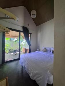 a bedroom with a white bed and a large window at Mini Village in Batukaras