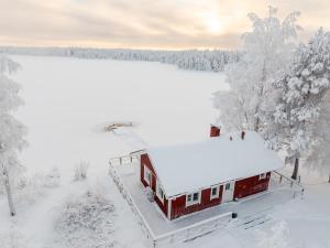 a house covered in snow in the woods at Lapland Heritage Villa in Ranua