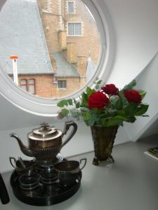 a vase of roses and a tea kettle and a window at Abeelboom B and B in Middelburg