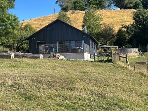 a black barn in a field next to a field of grass at Fortuna views farm stay in Jumbuk