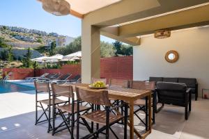 a patio with a table and chairs next to a pool at Cicada Villa in Koskinou