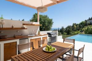 a kitchen and dining table with a view of a pool at Cicada Villa in Koskinou