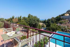 a balcony with a table and a swimming pool at Cicada Villa in Koskinou +27 photos