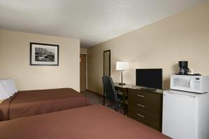 a hotel room with two beds and a desk with a microwave at Super 8 by Wyndham Saginaw in Saginaw
