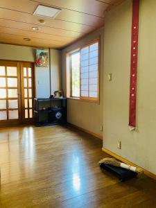 an empty room with a hard wood floor and windows at 春日旅館-Kasuga Ryokan- in Nabari