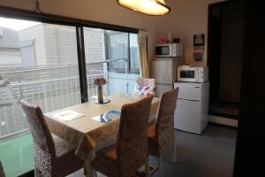 a dining room table with chairs and a kitchen with a window at KazenoKi in Kichijōji