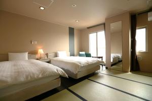 a hotel room with two beds and a mirror at Dormy Inn EXPRESS Asakusa in Tokyo