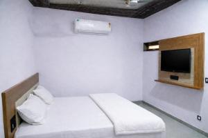 a white room with a bed and a tv at The Shree Ganesh Hotel in Khātu