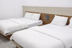 two beds in a room with white sheets and pillows at The Shree Ganesh Hotel in Khātu +3 photos